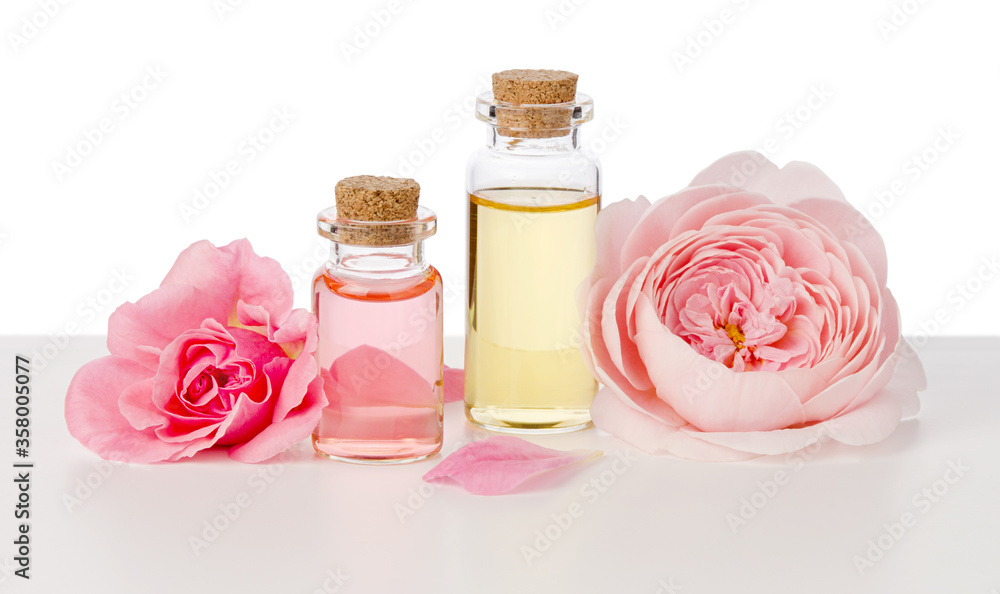Rose water and oil in glass bottles and pink flowers isolated on white background Rose water and oil in glass bottles and pink flowers isolated on white background