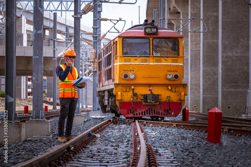 Engineer under inspection and checking construction process railway switch and checking work on railroad station .Engineer wearing safety uniform and safety helmet in work and radio communication.