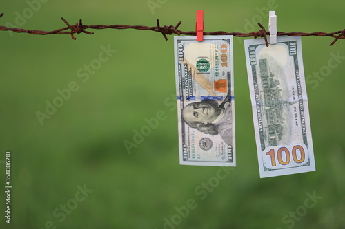 Money Laundering. Money Laundering US Dollars Hung Out To Dry. 100 Dollar Bills Hanging On Rusty Barbed Wire
