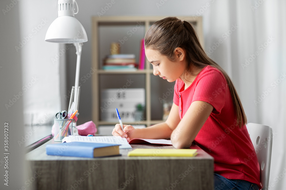 children, education and learning concept - student teenage girl with book writing to notebook at home children, education and learning concept - student teenage girl with book writing to notebook at home