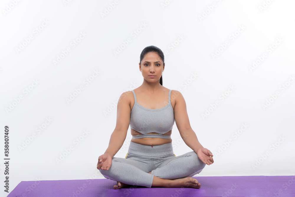 Young woman doing yoga and meditating on exercise mat Young woman doing yoga and meditating on exercise mat