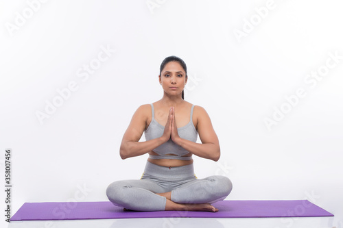 Young woman doing yoga and meditating on exercise mat  © G-images