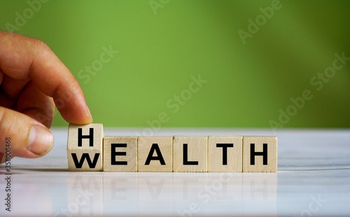 Hand changes the word "Health" to "Wealth"