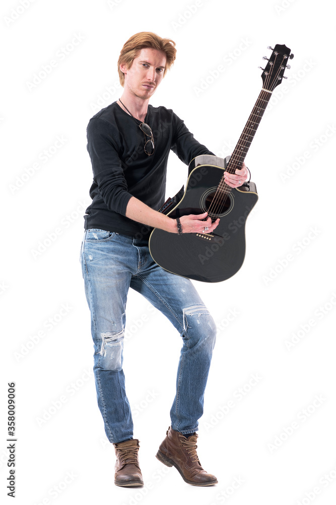 Self assured handsome guitarist playing acoustic guitar looking at camera. Full body length isolated on white background. Self assured handsome guitarist playing acoustic guitar looking at camera. Full body length isolated on white background.