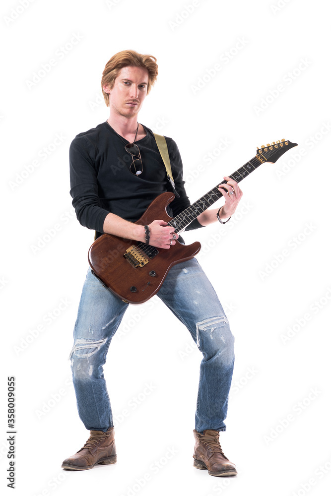 Confident hard rock music guitarist playing electric guitar looking at camera. Full body length isolated on white background. Confident hard rock music guitarist playing electric guitar looking at camera. Full body length isolated on white background.
