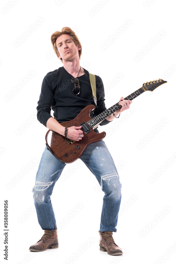 Emotional rock musician playing hard rock music on electric guitar looking at camera. Full body length isolated on white background. Emotional rock musician playing hard rock music on electric guitar looking at camera. Full body length isolated on white background.