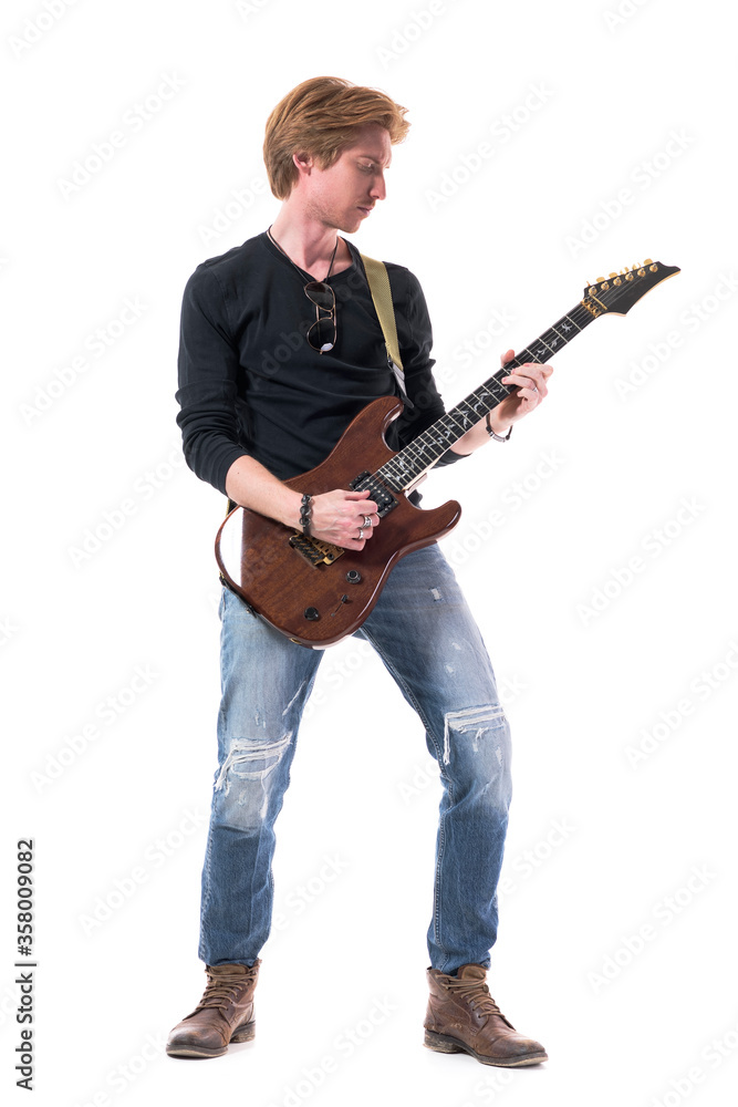 Cool relaxed young rocker guitarist man practicing and rehearsing electric guitar. Full body length isolated on white background. Cool relaxed young rocker guitarist man practicing and rehearsing electric guitar. Full body length isolated on white background.