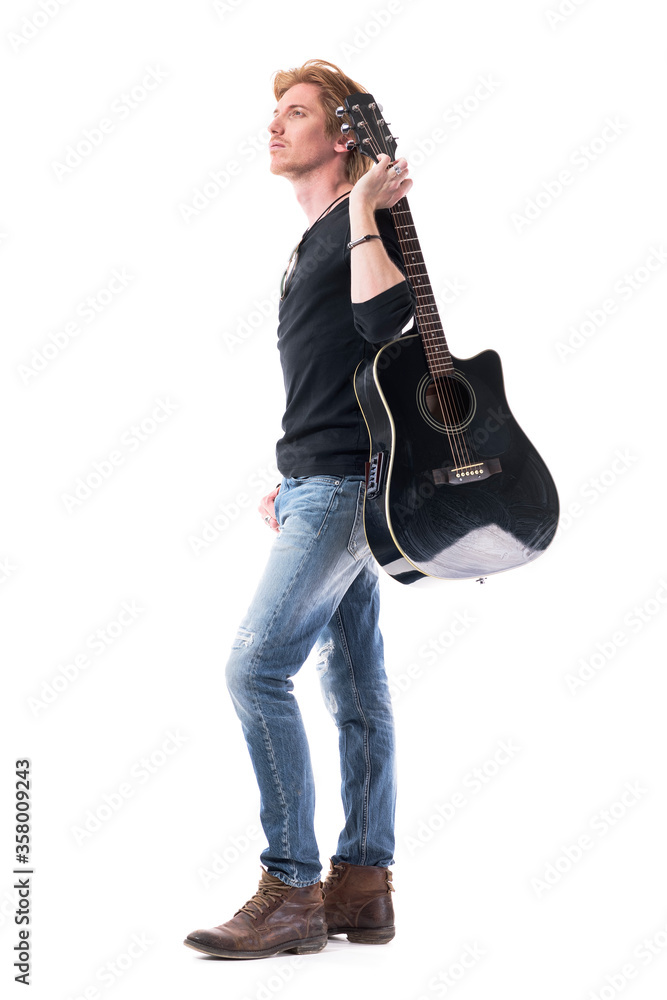 © sharplaninac - Confident young rocker man musician holding guitar looking up for inspiration ideas. Full body length isolated on white background.