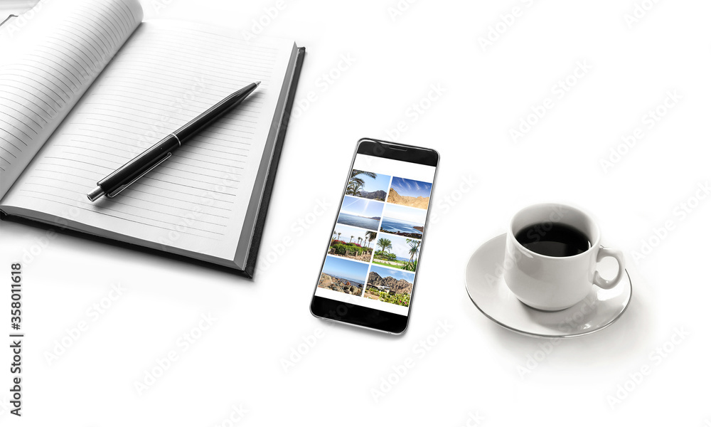 Notebook, pen, mobile phone with vacation pictures, and a cup of coffee isolated on white desk. Planning holidays and travel Notebook, pen, mobile phone with vacation pictures, and a cup of coffee isolated on white desk. Planning holidays and travel
