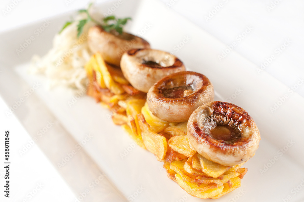 Fried potatoes with mushrooms on a white plate Fried potatoes with mushrooms on a white plate