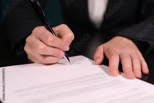 Woman signs a contract, close-up of hands with pen on paper