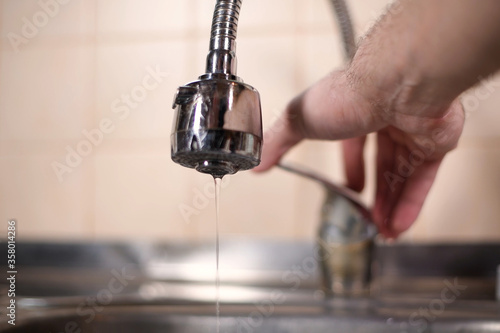 Schilderij op canvas a man opens a faucet in the kitchen, but no water comes