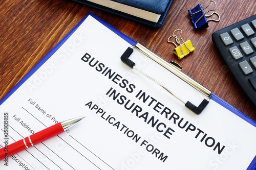 Business interruption insurance form and red pen for signing.
