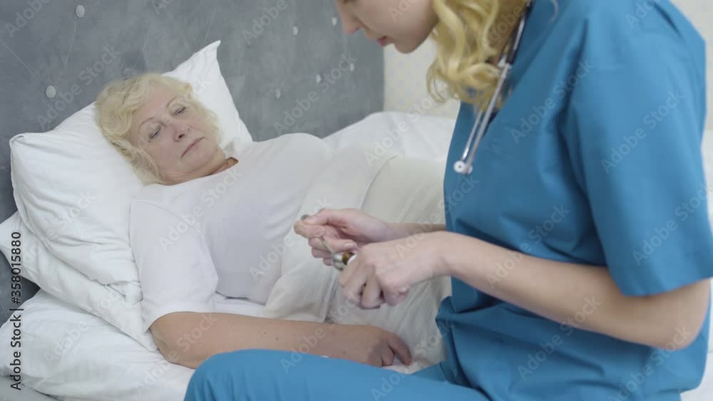 Nurse helping sick old woman to take medicines, healthcare and support at home Nurse helping sick old woman to take medicines, healthcare and support at home