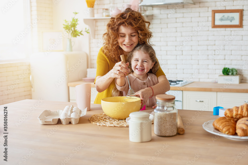Mother and daughter prepare a cake together in the kitchen