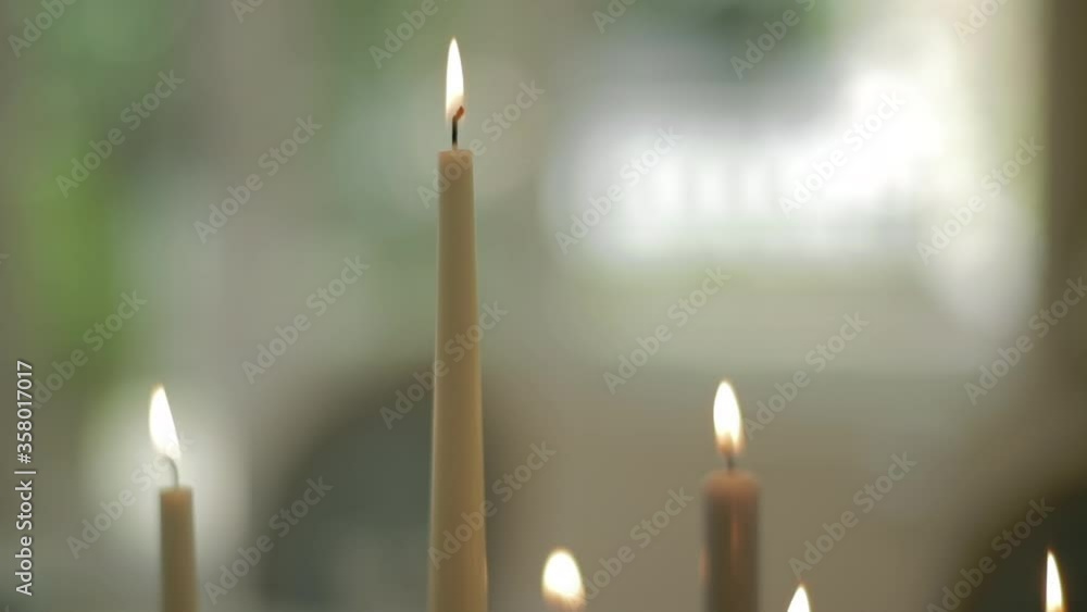 Top of candles burning with white roses in the background Top of candles burning with white roses in the background