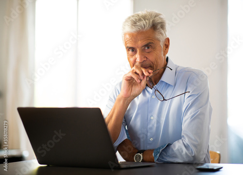 older businessman sitting at table with laptop