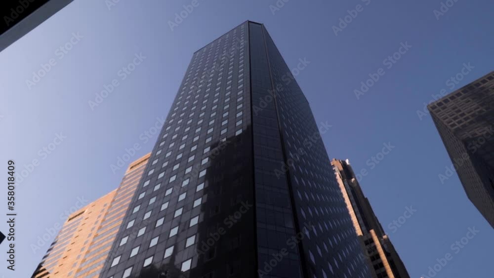 Up view of black Manhattan Skyscraper in slow motion during sunny weather with no clouds in New York City. Up view of black Manhattan Skyscraper in slow motion during sunny weather with no clouds in New York City.