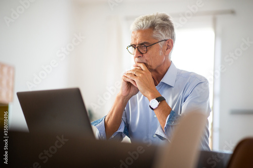 older businessman sitting in office looking at laptop