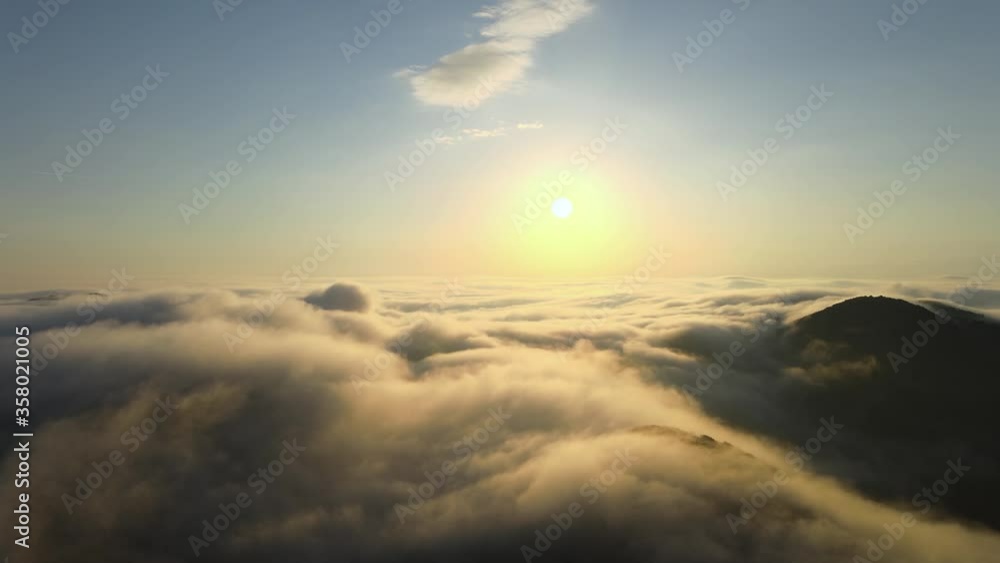 Drone fly over the sea of clouds with mountain landscape hill peak and sunshine during a sunrise with the sun up to the blue sky. Near Death Experience aerial footage concept Drone fly over the sea of clouds with mountain landscape hill peak and sunshine during a sunrise with the sun up to the blue sky. Near Death Experience aerial footage concept