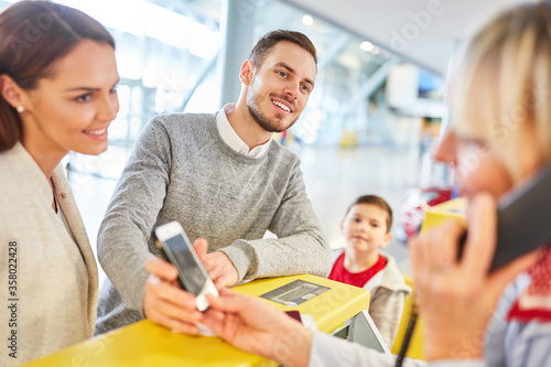Familie mit Smartphone am Check-In Schalter