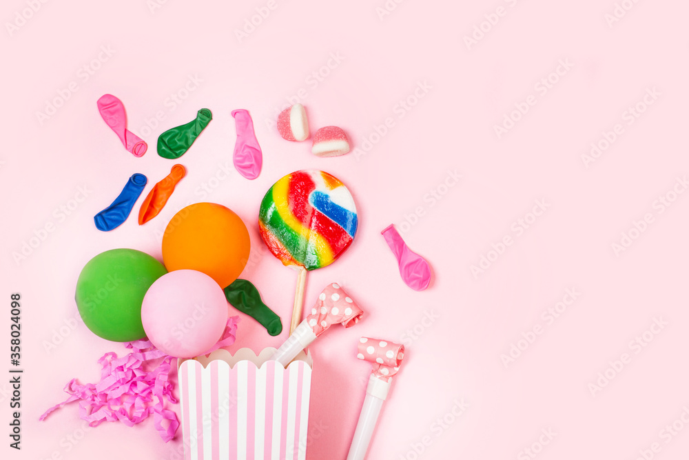 Caja de cumpleaños con globos, piruletas de colores y confeti sobre un fondo rosa liso y aislado. Vista superior. Copy space Caja de cumpleaños con globos, piruletas de colores y confeti sobre un fondo rosa liso y aislado. Vista superior. Copy space