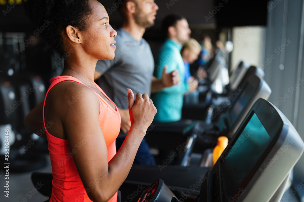 People running on treadmill in gym doing cardio workout People running on treadmill in gym doing cardio workout