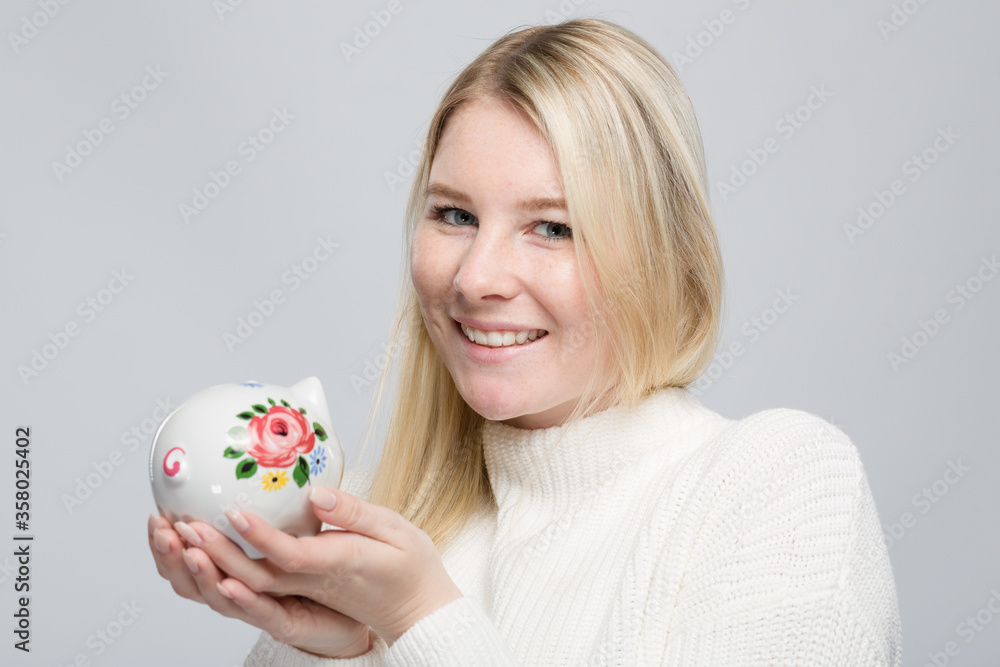 Smiling young woman with her colorful piggy bank Smiling young woman with her colorful piggy bank