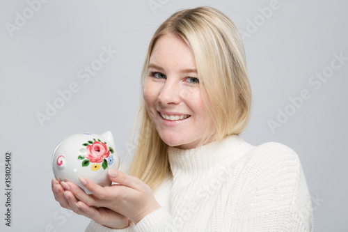 Smiling young woman with her colorful piggy bank