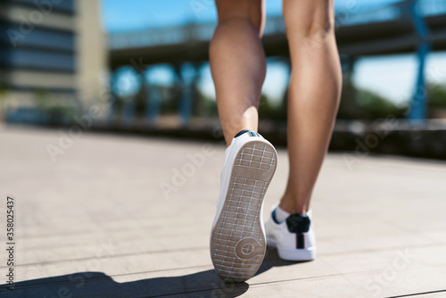 Morning jogging and running on the street. Closeup of the legs of a young athlete woman in sneakers. Sports and healthy lifestyle concept.