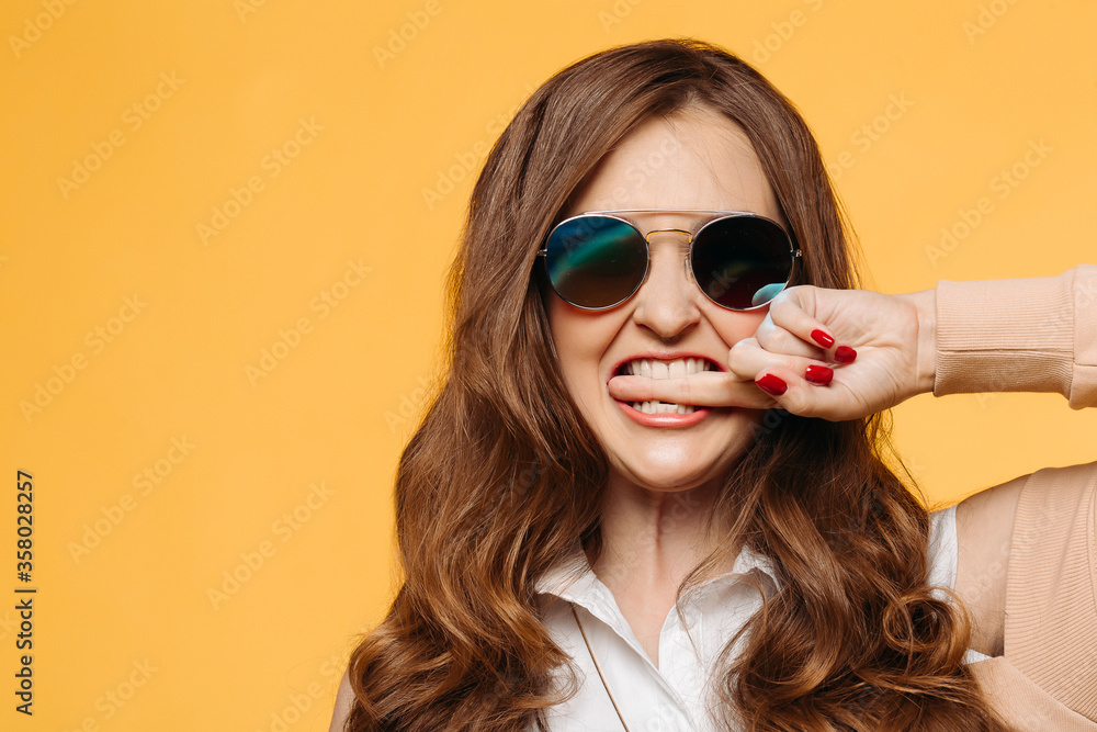 Stylish beautiful brunette woman with wavy hair, perfect make up after beauty salon,wearing in dress, posing with hand on waist, crossed legs. Beige studio background.Concept of shopping and fashion.