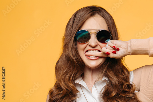 Stylish beautiful brunette woman with wavy hair, perfect make up after beauty salon,wearing in dress, posing with hand on waist, crossed legs. Beige studio background.Concept of shopping and fashion. © Вячеслав Косько