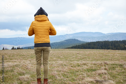 Fotografie Woman enjoying in the nature with hilly landscape in the background