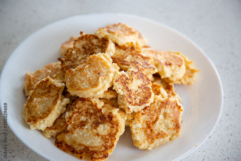round fried golden curd cheesecakes on a white round plate, white background round fried golden curd cheesecakes on a white round plate, white background