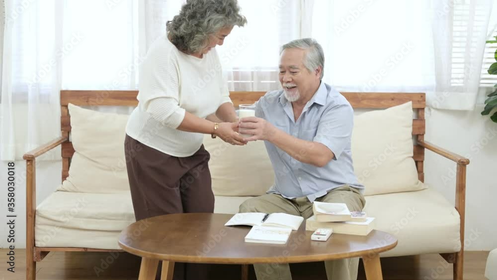 Asian elder wife give a cup of milk to her Asian husband. Elder healthy, Good food good mood, happy retirement concept. Asian elder wife give a cup of milk to her Asian husband. Elder healthy, Good food good mood, happy retirement concept.