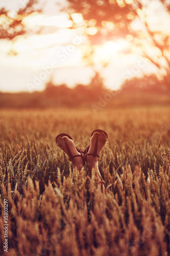 Woman's feet with genie sandals in a wheat field.