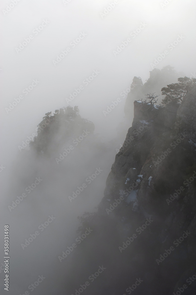 Winter mountain peaks in dense fog