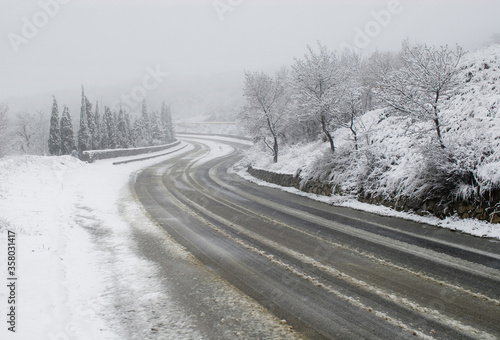 Curved road in winter with traces of a car during a snowfall