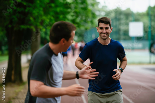 Young men training on a race track. Two young friends running on athletics track