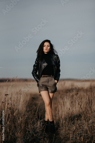 fashion girl in a leather jacket and shorts poses stylishly