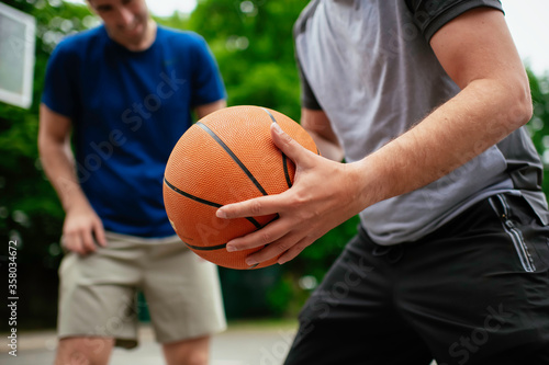 Close up of hands holding ball. Friends playing basketball in the park. © JustLife