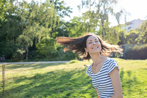 Young caucasian woman in the park with flying hair