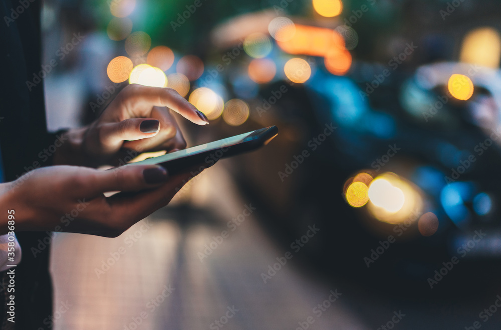 Close up female hand calling taxi with a smartphone app., businesswoman using cellphone with yellow taxi background in night street