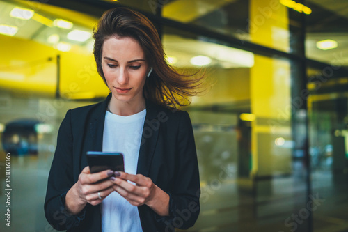 Obraz na płótnie portrait professional female finance lawyer standing near office in evening street communicates online by cellphone. successful businesswoman pushing message to colleagues on mobile yellow neon lights w salonie
