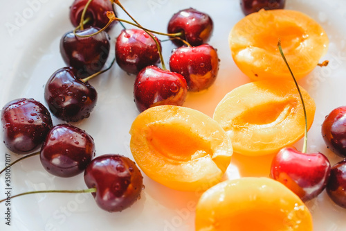 Slices of apricots and cherries on a white plate. Summer fruits and berries.