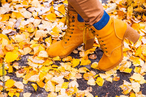 Women's orange boots on the background of yellow foliage.