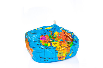 Planet earth toy balloon deflated isolated on white background. Earth overshoot day, unsustainable resources consumption concept