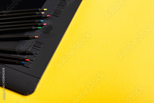 Close up view of color pencils on graphics tablet on yellow surface