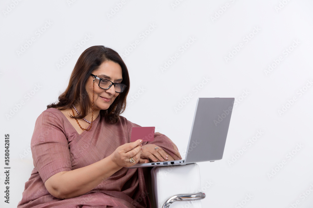 Fototapeta premium Woman doing online shopping using credit card and laptop at home.