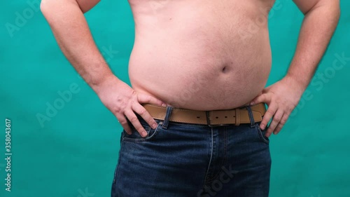 male with a big belly shows his fat on a green screen. The concept of healthy eating and losing weight, diet
